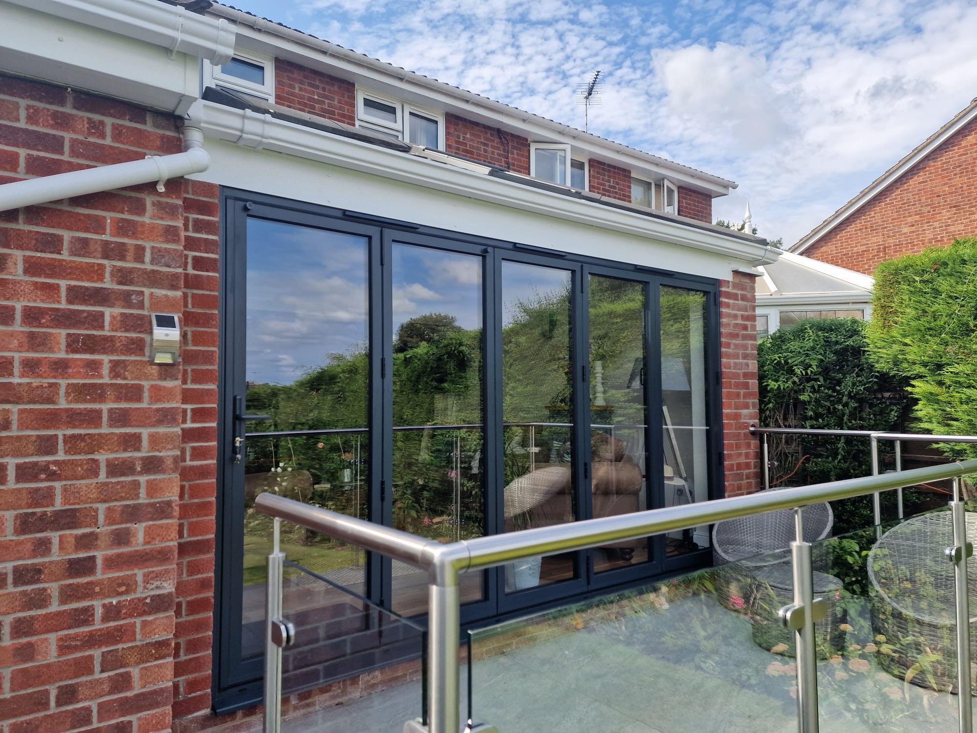 Set of 4 bifold doors on a brick house with a balcony rail